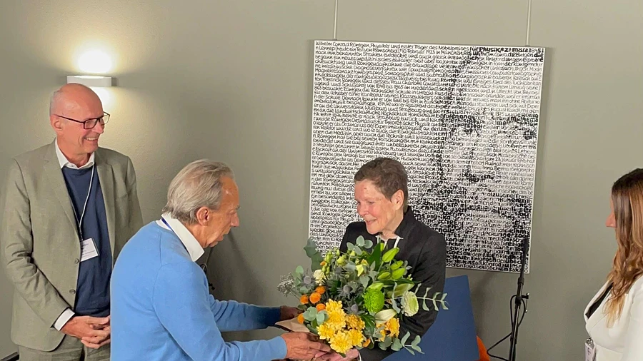 Ein Mann überreicht einer Frau einen bunten Blumenstrauß bei einer offiziellen Zeremonie.